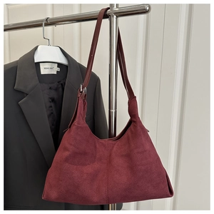 Macro detail of burgundy suede tote bag with vertical stitching and silver buckle