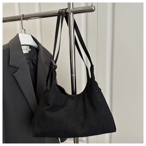 Close-up of black matte suede tote bag hanging on hanger with professional business attire