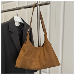 Detailed view of brown suede hobo bag featuring vertical stitching and smooth leather strap