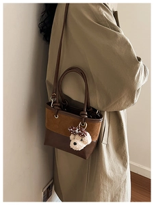 Detailed shot of brown suede patchwork bucket bag featuring a cute teddy bear charm