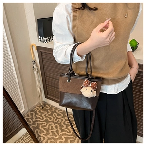 Detail of suede patchwork bucket bag with cute plush bear charm and crossbody strap