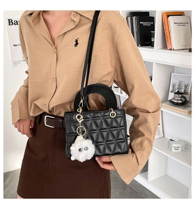 Détail d'un sac à bandoulière matelassé noir avec dorures et breloque chat en peluche