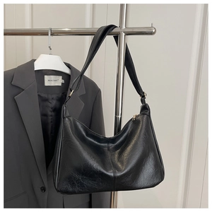 Detail der schwarzen Hobo-Tasche mit glänzender Kunstledertextur und Schultergurt