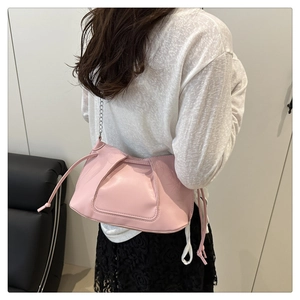 Detail of light pink pleated shoulder bag with metal chain strap on female model
