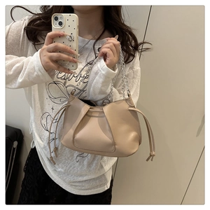 Close-up of beige pleated shoulder bag featuring silver metal chain and drawstring details