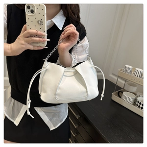 Detailed view of white pleated leather shoulder bag with metal chain and drawstring accents