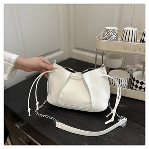 Close-up of white pleated leather bag with silver chain strap and drawstring details