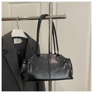 Detail of black glossy patent leather shoulder bag with vintage texture on a hanger