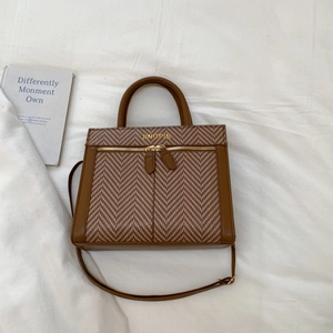 Détail d'un sac à main marron à carreaux avec double fermeture éclair et poignée ronde