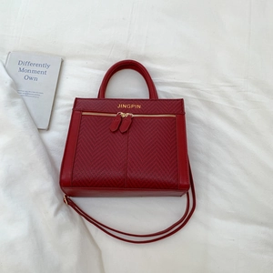 Détail d'un sac à main rouge en similicuir avec texture à chevrons et logo doré