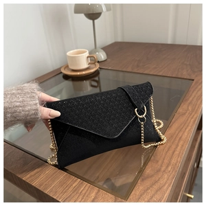 Détail de la pochette enveloppe noire tricotée avec fine bandoulière dorée