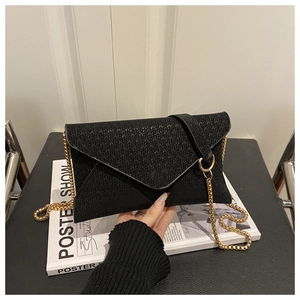 Détail d'une pochette enveloppe noire avec texture en V et bandoulière dorée
