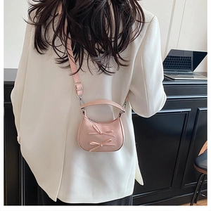 Gros plan du sac à bandoulière rose clair avec nœuds en cuir mat et bandoulière réglable