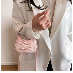 Sac à bandoulière rose à nœuds porté avec un blazer blanc pour un look de bureau chic