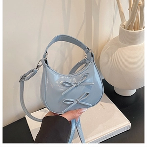 Vue détaillée du sac croissant bleu clair avec nœuds et bandoulière réglable