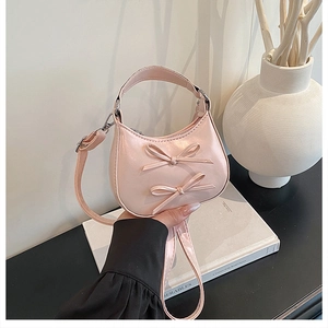 Détail du sac demi-lune rose avec double nœud décoratif et bandoulière réglable