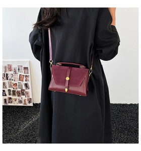 Detail of burgundy crossbody bag with contrast suede flap and gold metallic buckle
