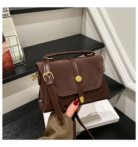 Detail view of vintage brown crossbody bag with suede stitching and gold metal buckle