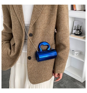 Detail of blue acrylic cylindrical crossbody bag with metallic handle and gold chain strap
