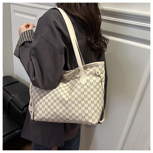 Detail of large tote bag with M-letter print and slim leather shoulder straps