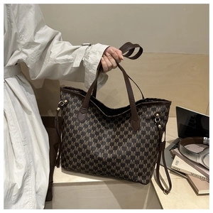 Detail of vintage monogram print tote bag with leather handles and gold metal hardware