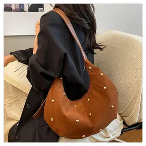 Detail of vintage brown suede crescent hobo bag with gold metal studs and wide leather strap