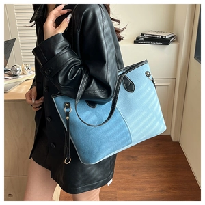 Close-up of large denim tote bag with black leather trim and contrast stitching details