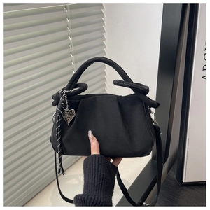 Détail du sac plissé noir avec texture mate, breloque coeur et sangle tressée