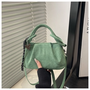 Détail du sac à main en daim plissé vert avec cordon tressé et pendentif en cœur