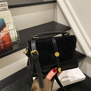 Minimalist black leather and suede crossbody handbag with gold circular metal buckle