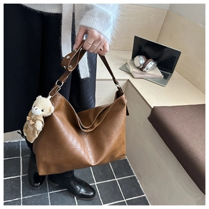 Dettaglio borsa tote vintage marrone con ciondolo a forma di orso e tracolla larga