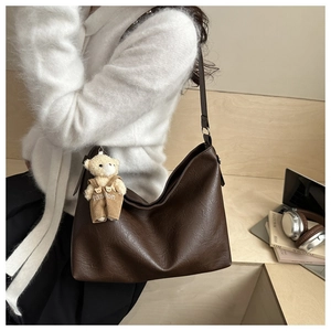 Dettaglio della borsa vintage marrone con grana litchi e ciondolo a forma di orso