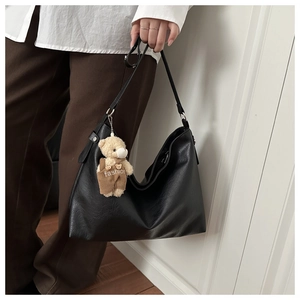 Dettaglio della borsa tote in ecopelle nera con ciondolo a forma di orso sulla tracolla