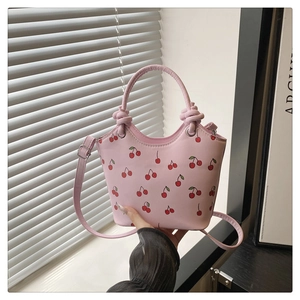 Detail van roze handtas met kersenprint, imitatieleer textuur en verstelbare riem