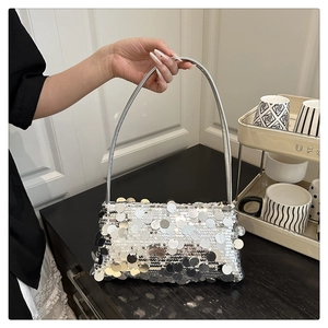 Silberne Pailletten-Schultertasche, von einem Model in modernem Ambiente gehalten