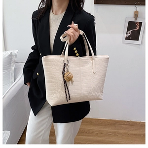 Detail of cream white faux crocodile leather tote bag with unique dice charm accessory