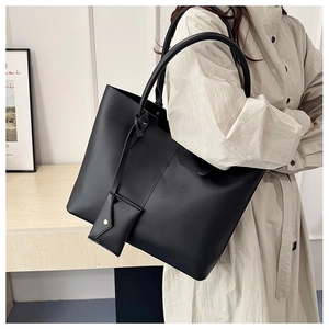 Detail of a black large tote bag with a matching mini pouch and elegant shoulder strap