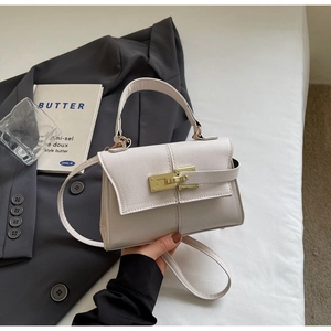 Close-up of cream textured leather mini bag with gold lock and sleek top handle detail