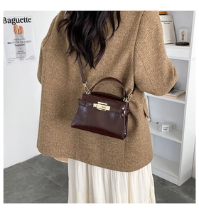 Detailed back view of a dark brown glossy leather crossbody bag with gold twist lock buckle