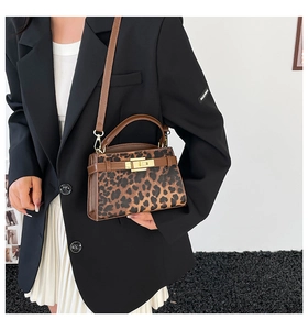 Close-up of leopard print handbag with brown leather handle and gold rotary lock buckle