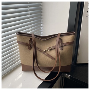 Detail of beige and brown leather tote bag with gold hardware and stylish拼接 design