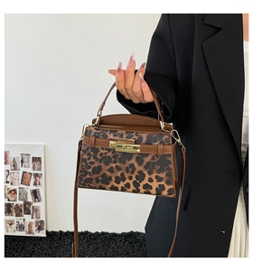 Detail of leopard print handbag with brown leather handle and gold twist lock closure