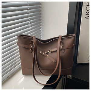 Detailed view of dark brown tote bag featuring pebbled leather texture and gold hook clasp