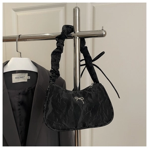 Detail of black pleated cloud bag with silver bow accent and ruffled shoulder strap
