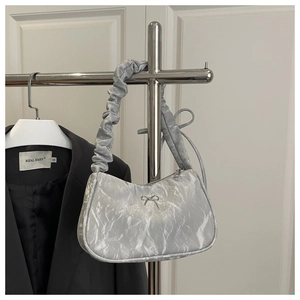 Close-up of pleated silver handbag featuring a metallic bow and scrunchie handle