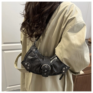 Close-up of black crescent bag with pleated leather, silver rivets, and buckle detail