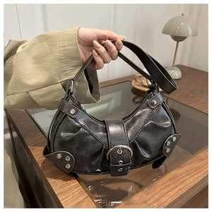 Detail of black punk crescent bag with silver rivets and vintage pleated leather texture