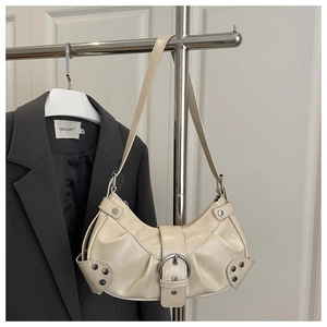 Detail of cream crescent bag featuring metal buckle, rivet accents and pleated texture