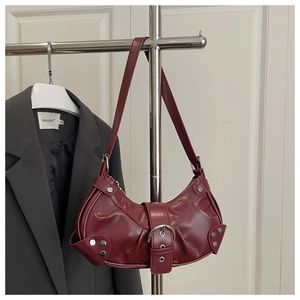 Detailed shot of a burgundy crescent motorcycle bag with silver rivets and metal buckle