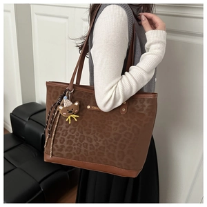 Detail of leopard print tote bag with brown leather trim and cute bear keychain